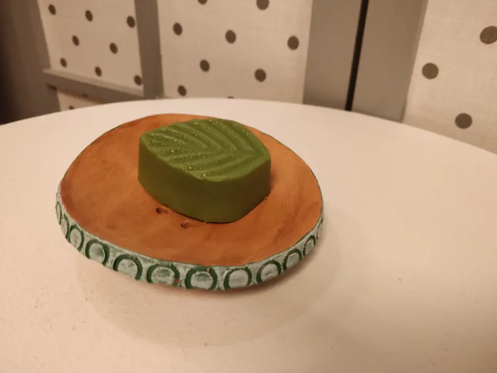 Savon à la sève de bouleau en forme de feuille, vert, sur un porte-savon en céramique créé par Laure Laforge, de l'atelier Au cOchOn dingue !